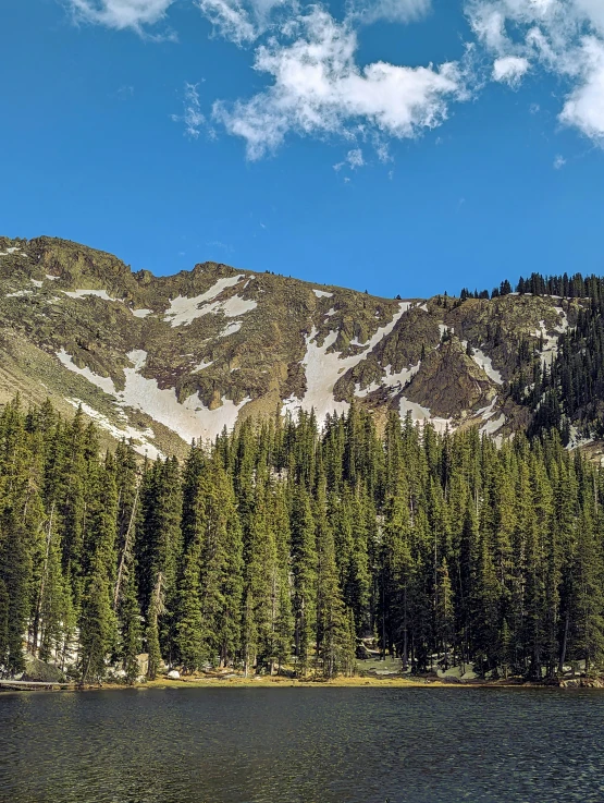 a mountain sits on top of a tree filled mountain