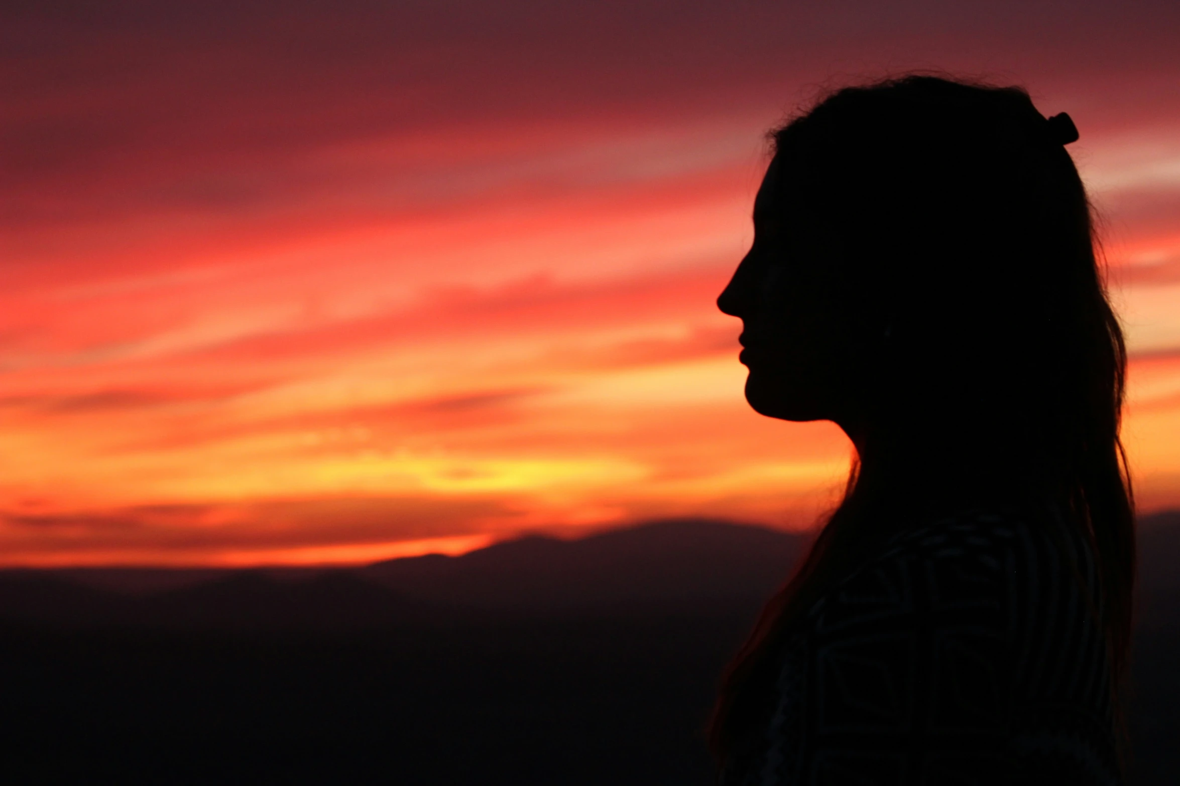 the silhouette of a person in front of an orange sunset