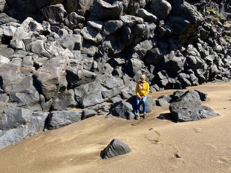 a man sitting on rocks next to an ocean