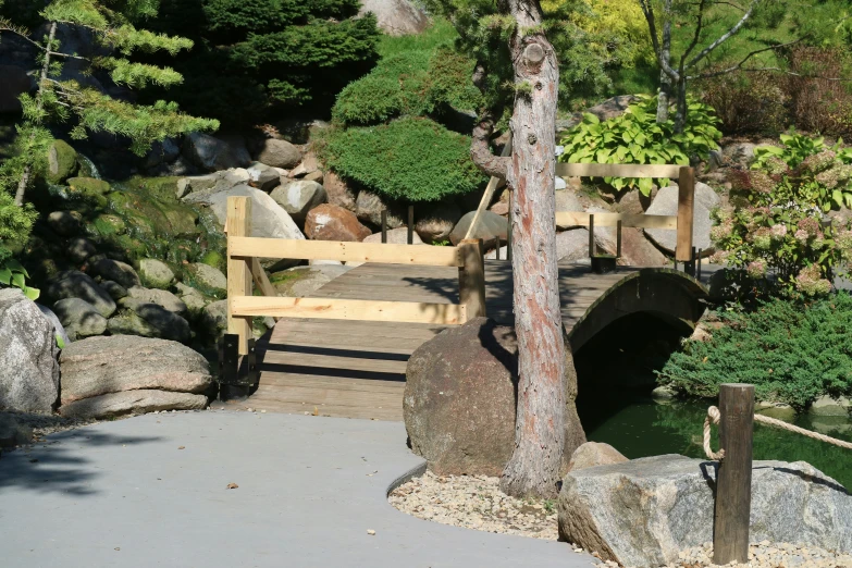 a stone covered path with trees, rocks and bridge