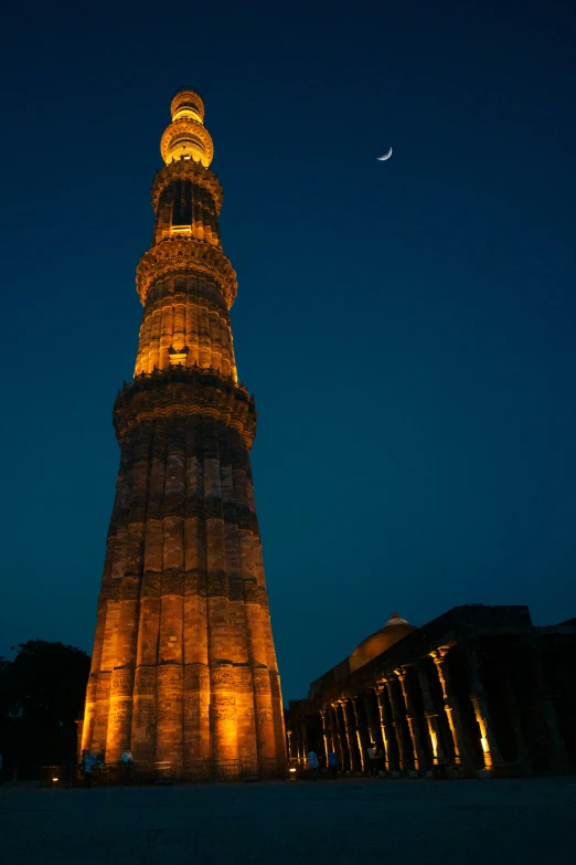 an illuminated tower stands over a building at night