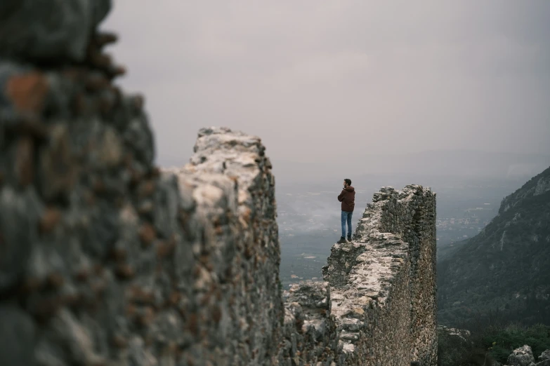 a person standing on a stone wall in a landscape