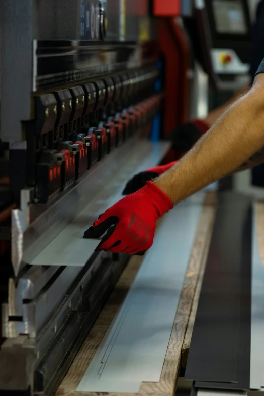 a man with red gloves is working on metal pieces