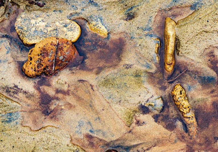 several rocks in the sand with water all around them