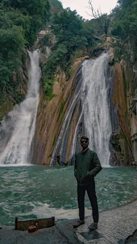 a man is standing by a waterfall