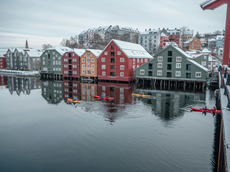 a group of buildings by a river with canoes in front