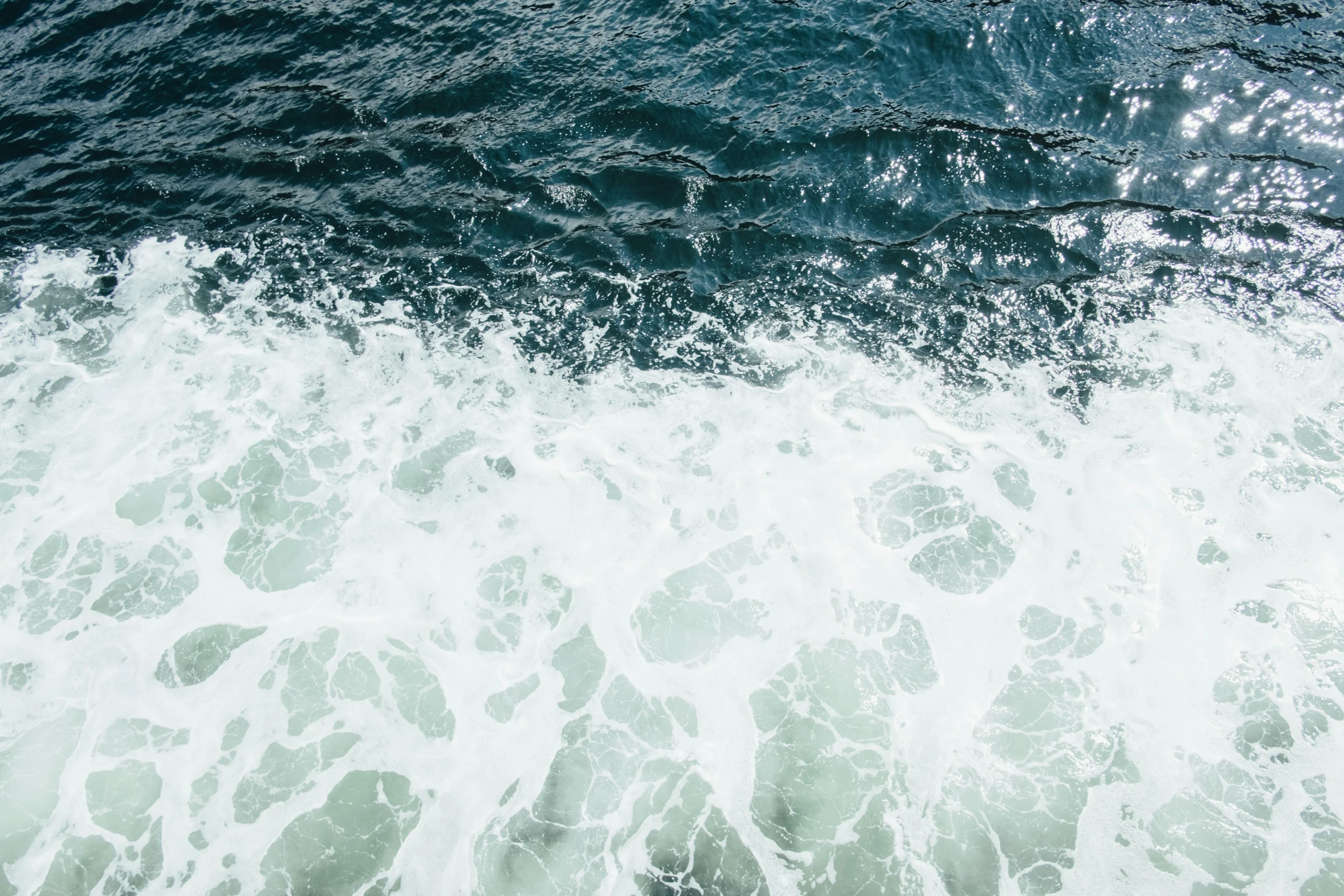 an aerial view of the ocean waves, looking down on the shoreline