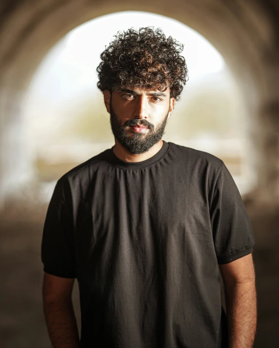 a bearded man in a black shirt is in the middle of a tunnel