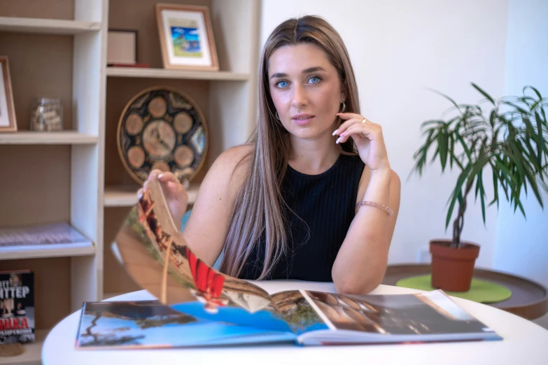 the woman is sitting at the desk with her book