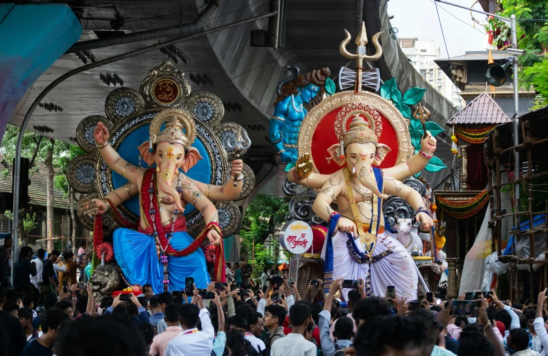 several elephants are lined up on a street with many people