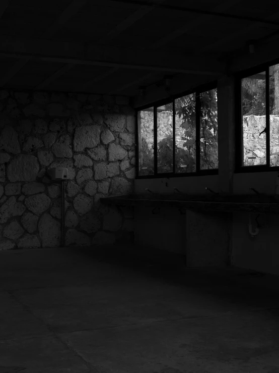 a dark room with several windows overlooking trees