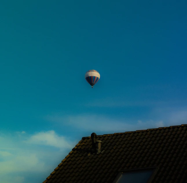 a  air balloon is flying over some roofs