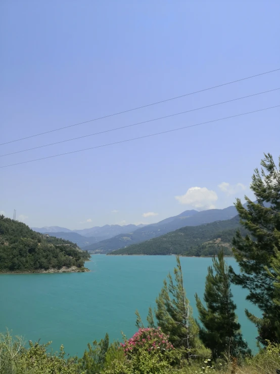 view of a lake with green hills and blue sky