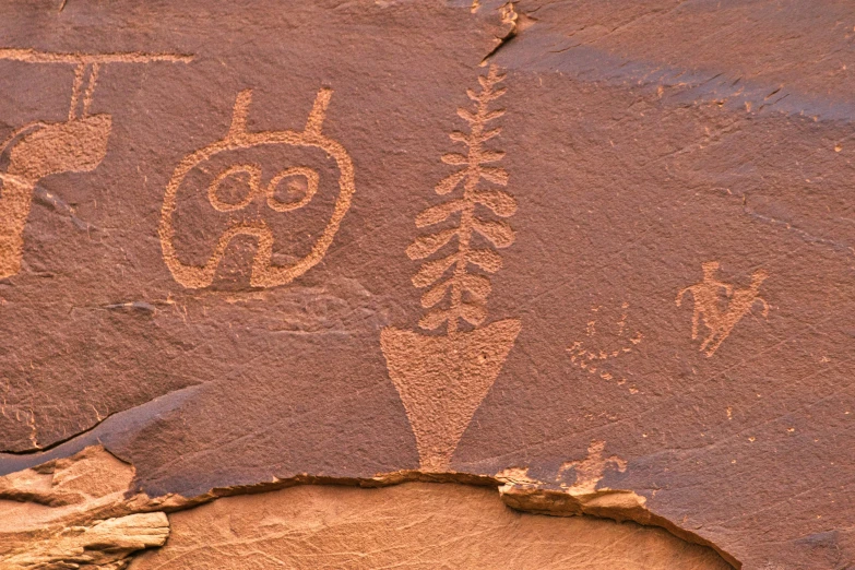 petroglynic figures carved in the sand with tree silhouettes