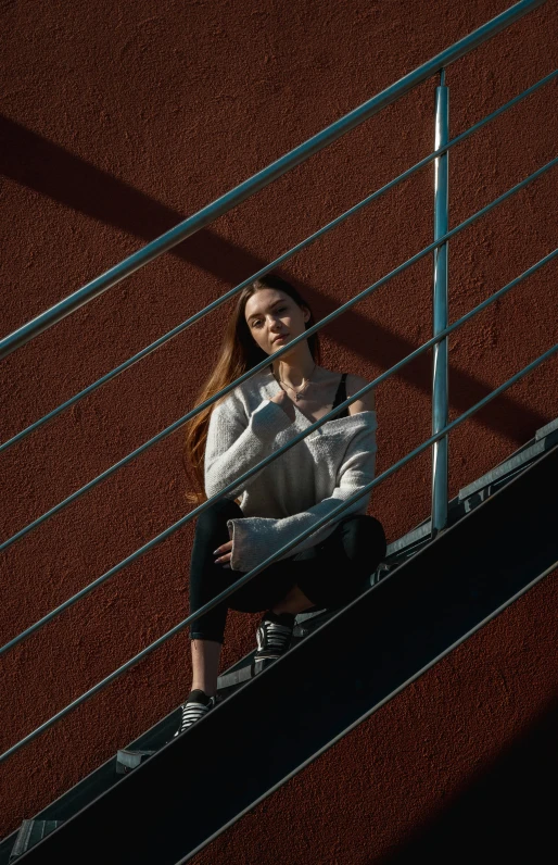 a girl sitting on the steps of a staircase with her cell phone in hand