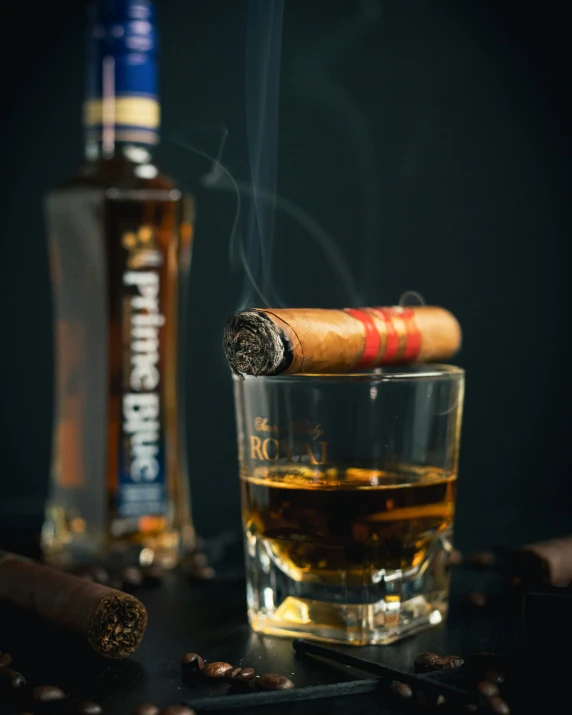 a cigar sitting on a glass with a cigarette on it