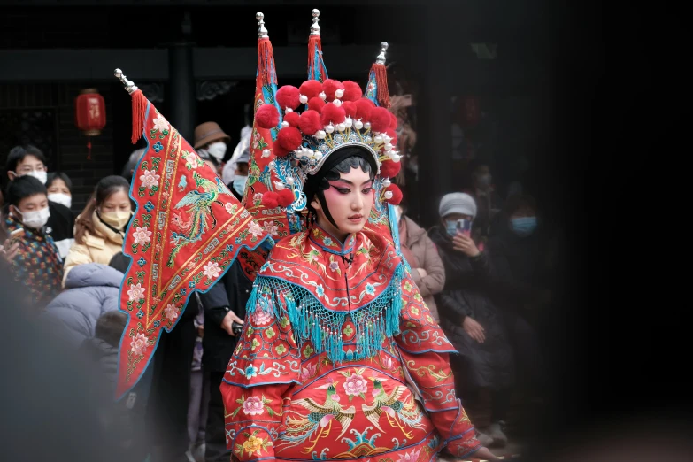 a chinese woman wearing an elaborate red and blue head dress and fan