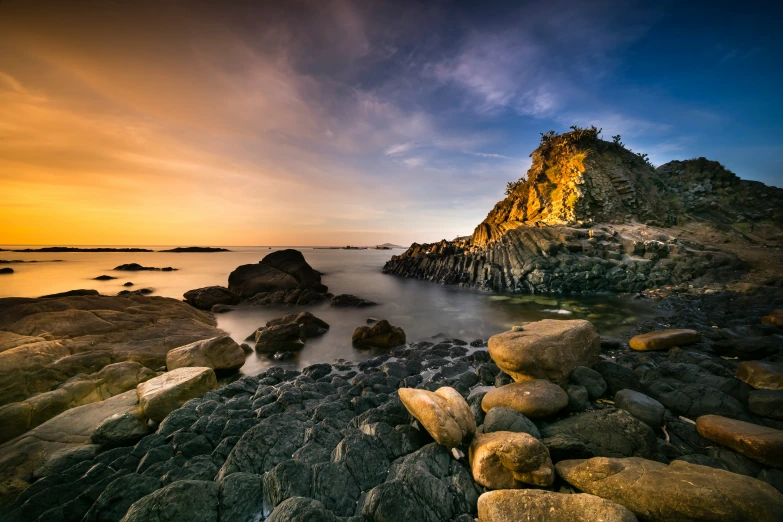 there are some rocks on the water and there is some land in the background