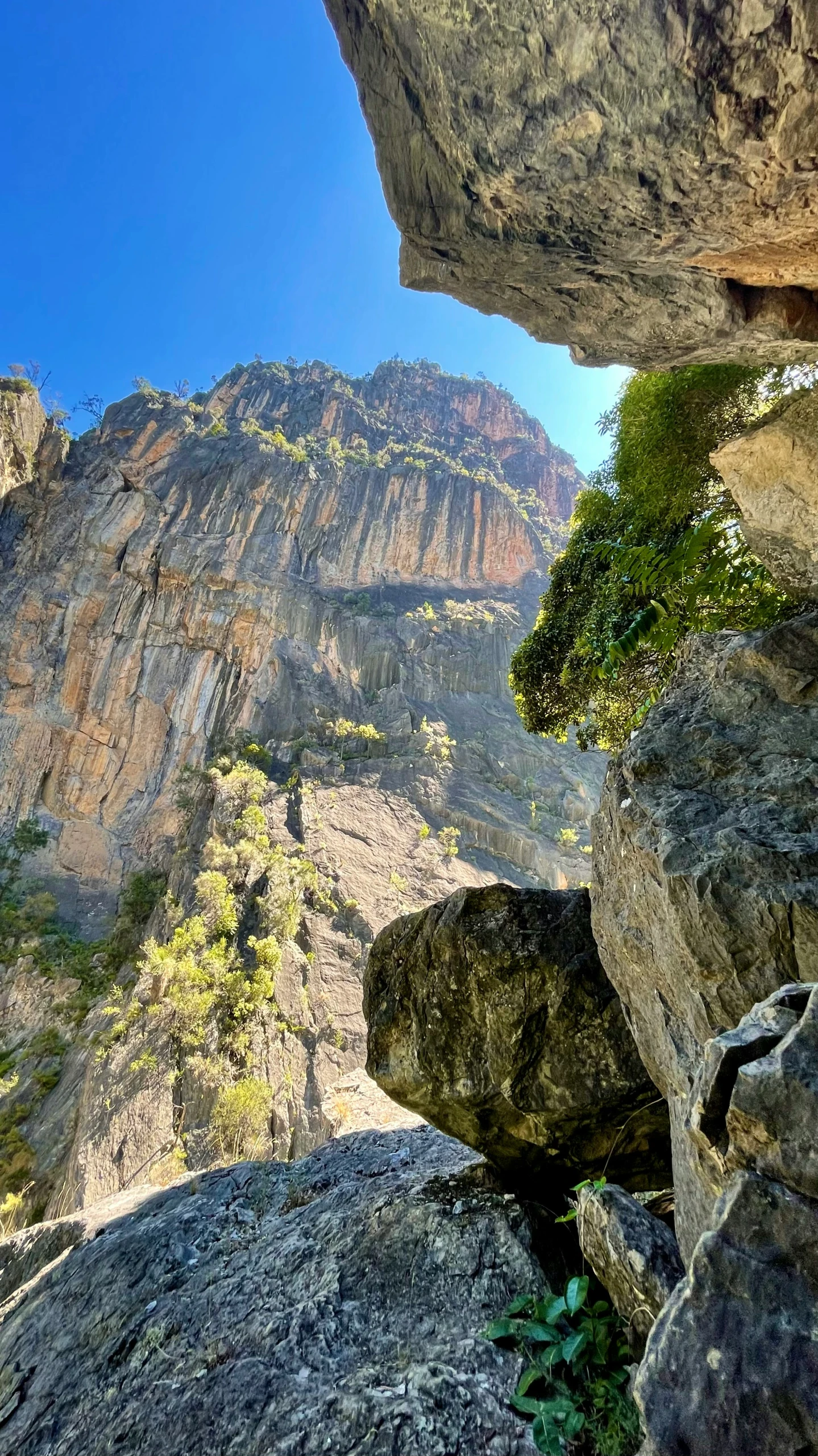 a large rocky cliff with a small gap in the center