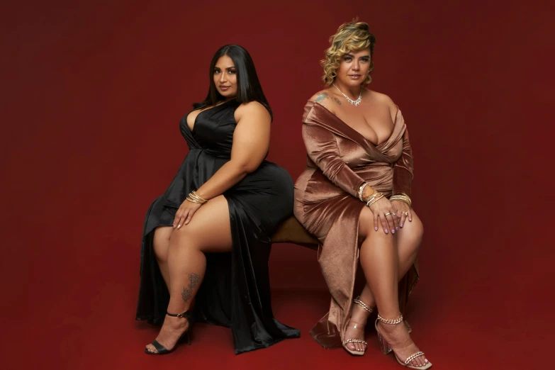 two women in black and gold dresses pose together