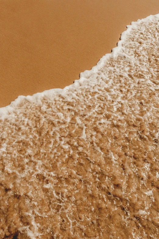 an airplane flying over the top of the ocean on a sandy beach