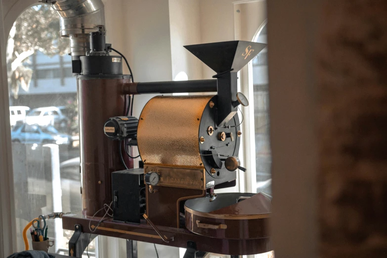 a large coffee grinder sitting on a desk near a window