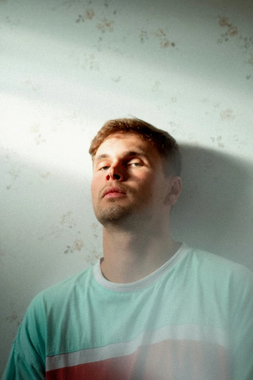 a man standing next to a wall with his eyes closed