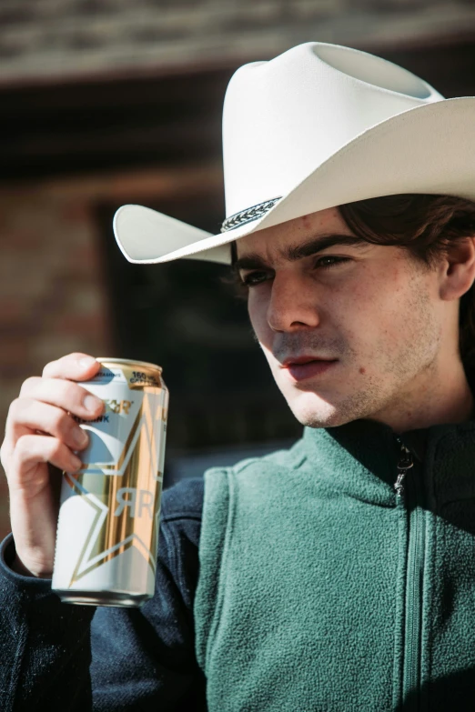 a young man in a hat drinking a can of beer