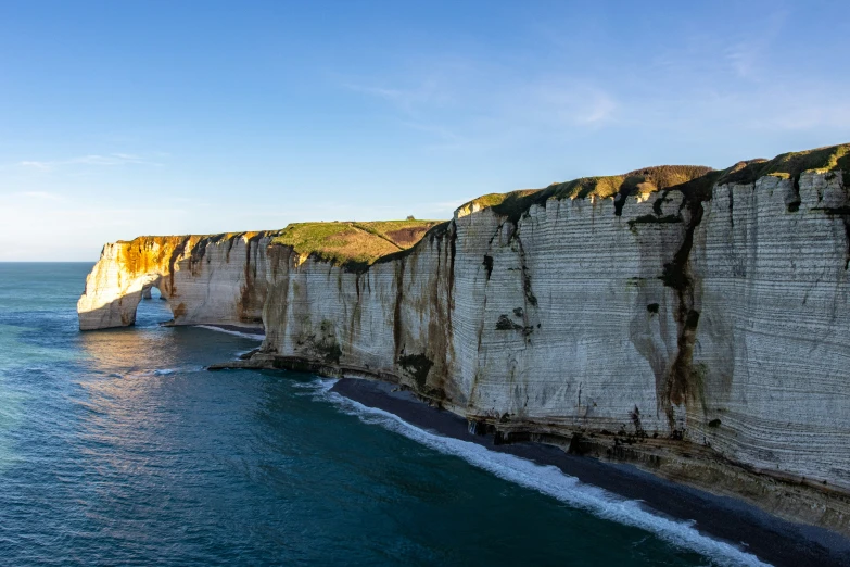 there is a rock cliff that is at the edge of the ocean