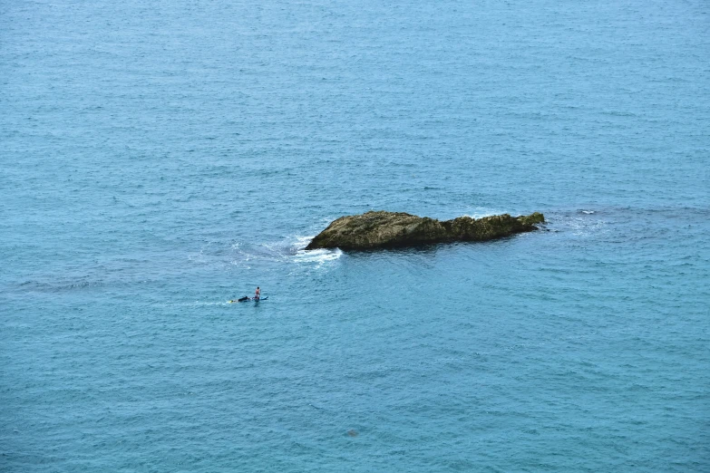 a lone boat sailing close to an island in the ocean