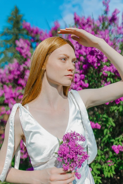 a woman holding a bouquet of flowers next to some pink trees