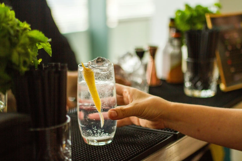 someone is holding a yellow stick next to a glass with water