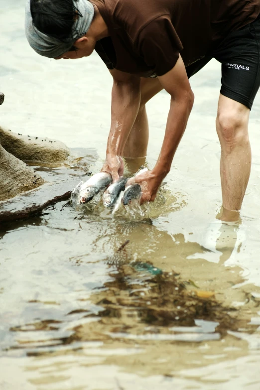 a man picking up several fish from the ocean