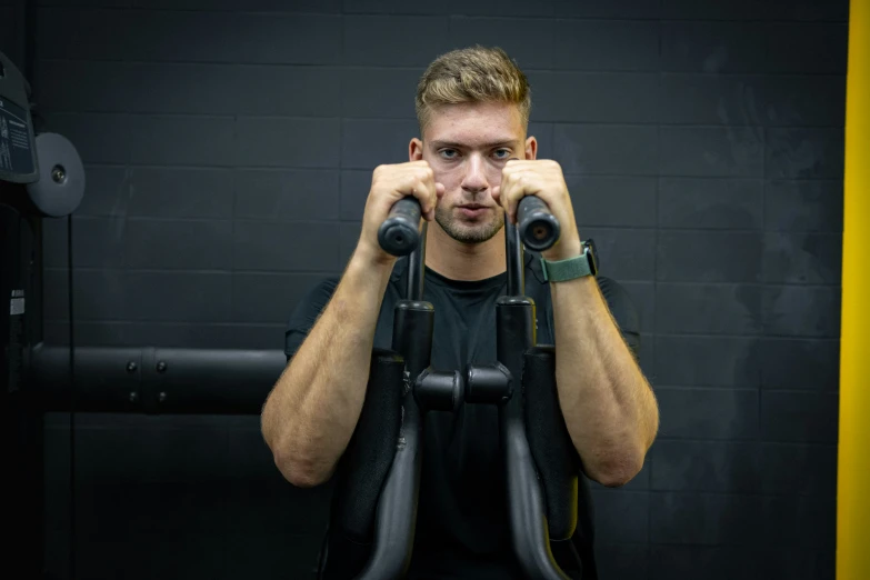 man sitting in gym doing exercises using barbells