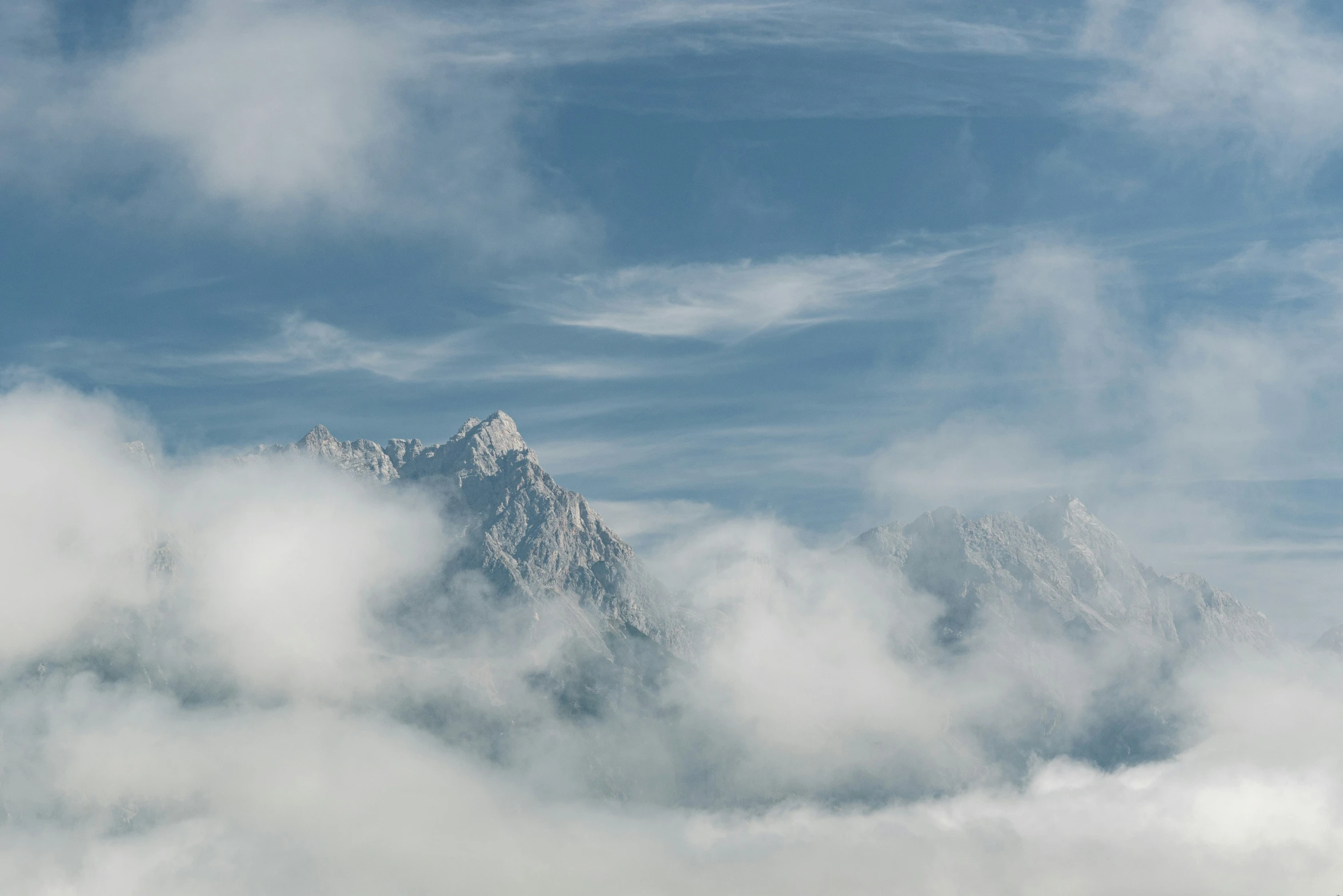 the mountains are covered with heavy clouds on a blue sky