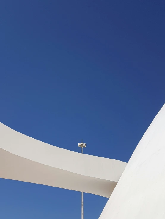 an overhanging white structure with bright streetlights, as the sun shines through