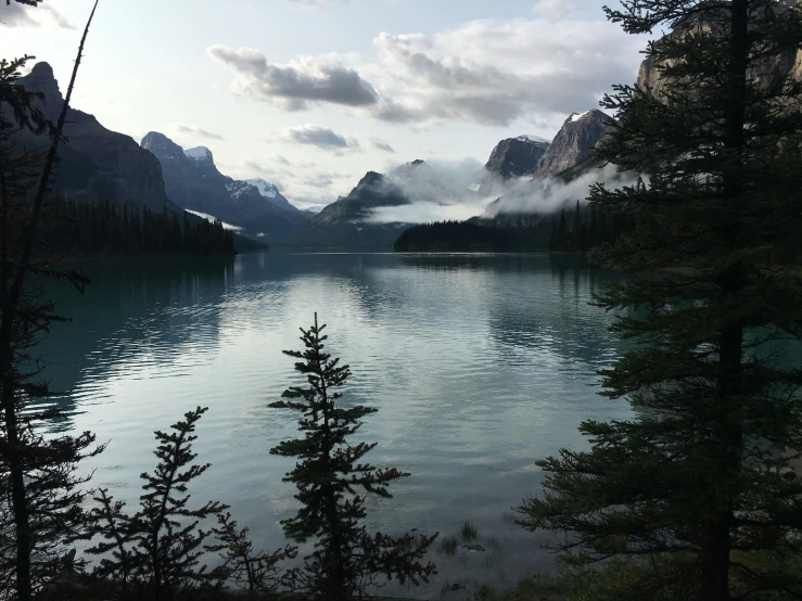 a lake surrounded by evergreen trees and mountains