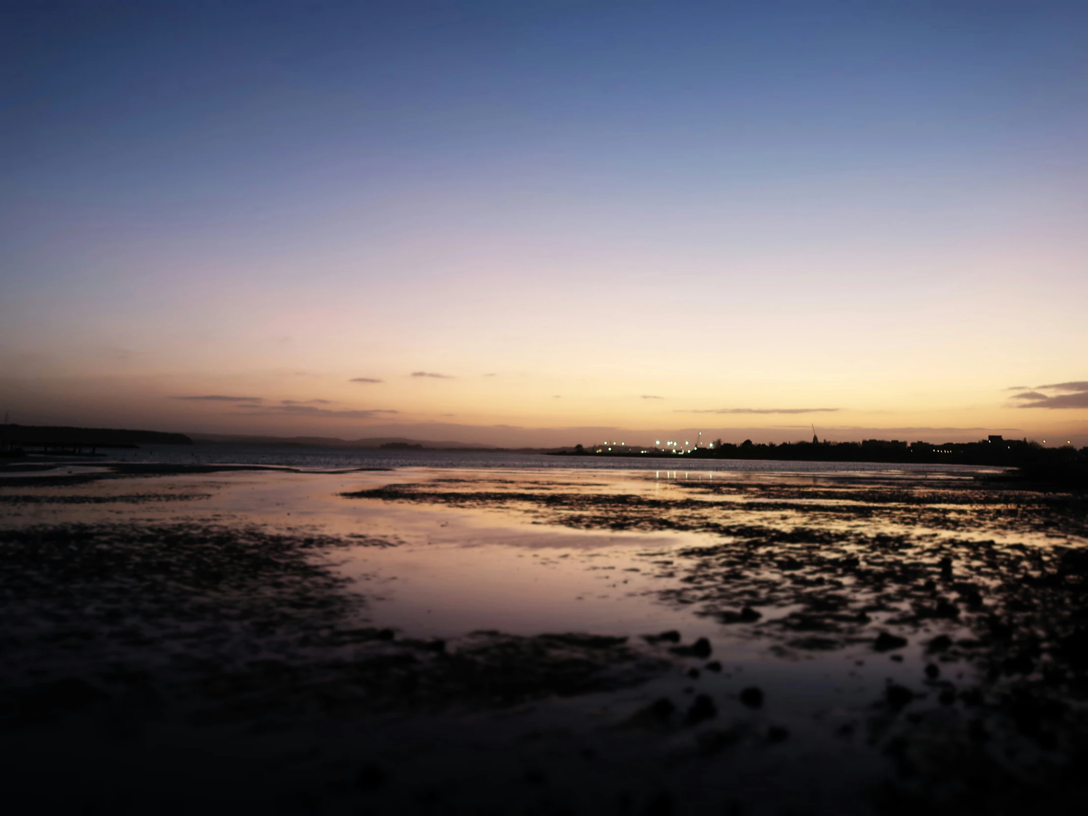 a sunset over the water with the shore line