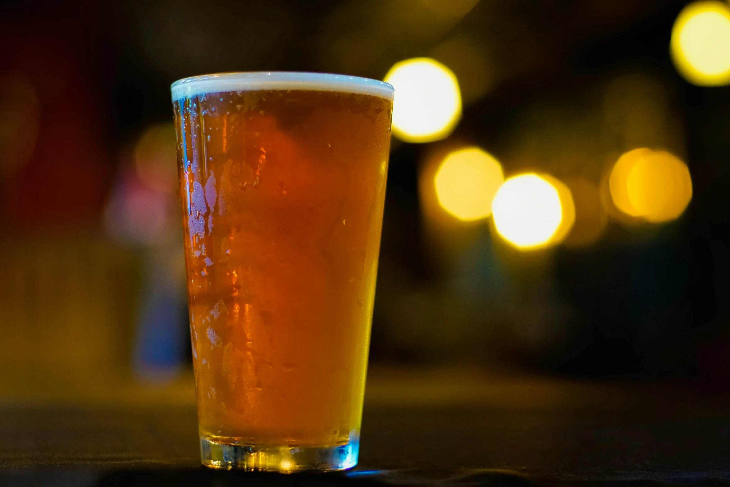 glass of beer is on the table in the dark