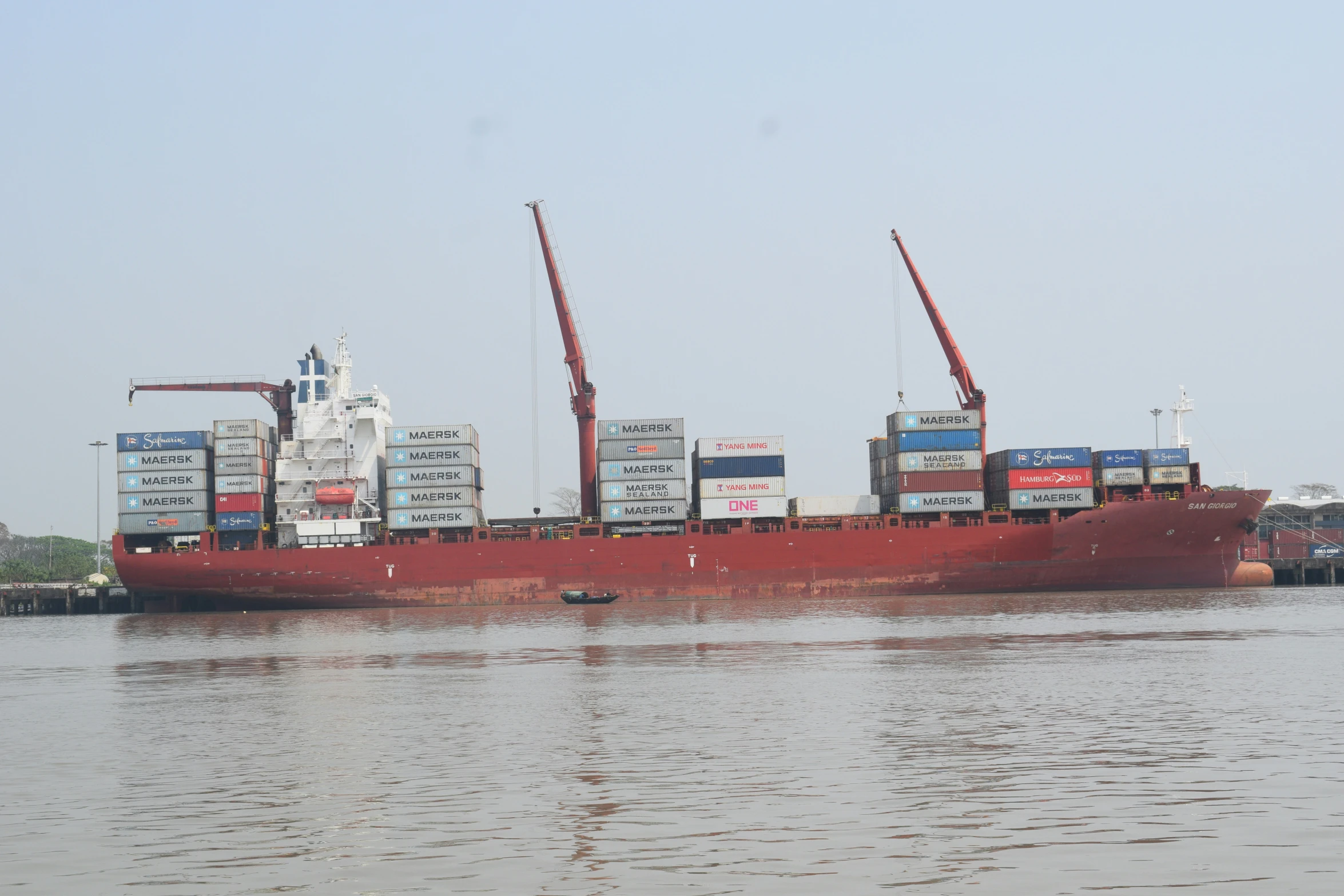 a red cargo ship traveling through the water