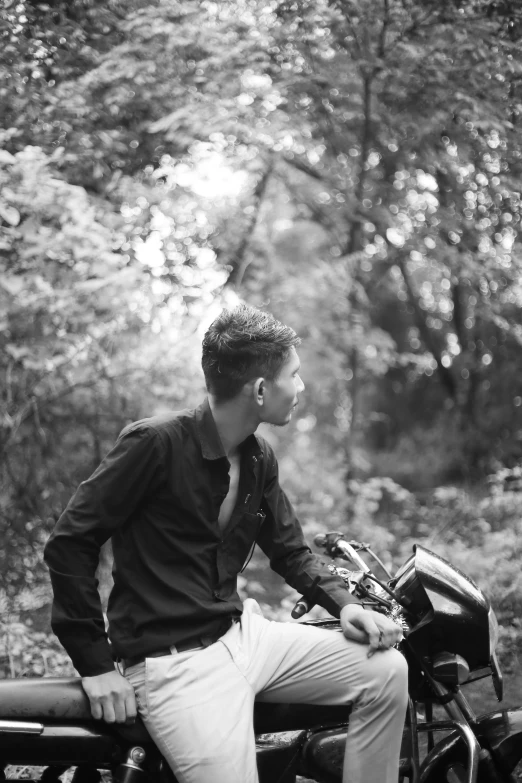 a young man wearing a baseball glove sitting on a bench in the woods