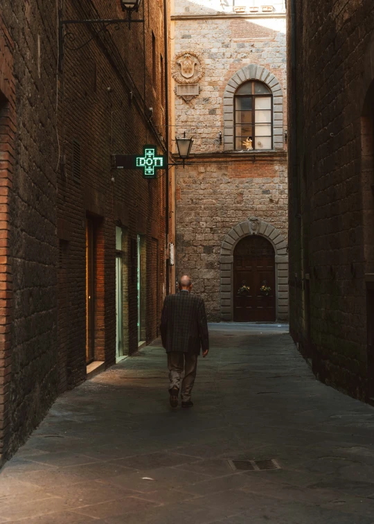 a man walking along a narrow street under bridges