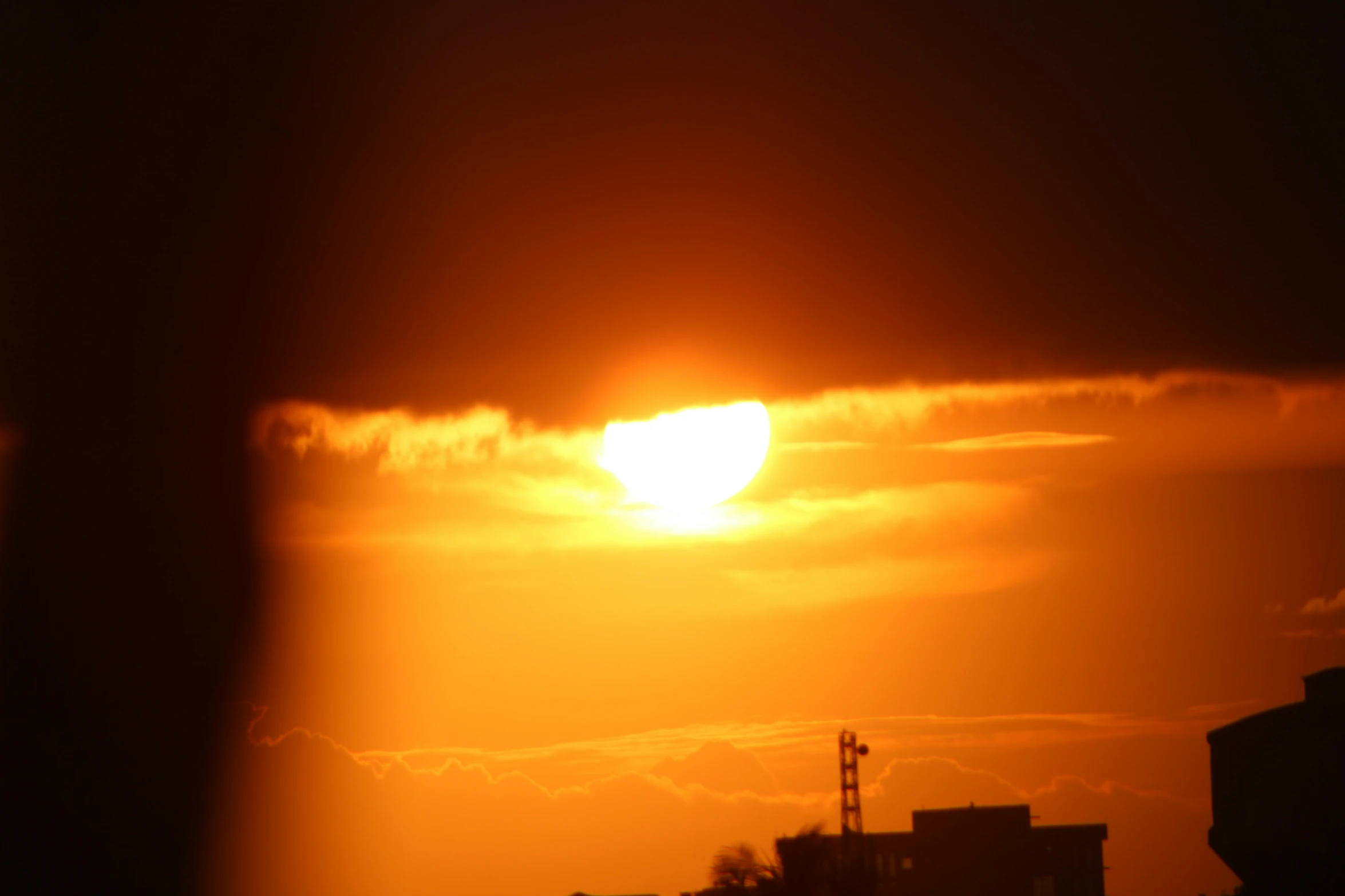 the sun setting with dark clouds in a dark sky