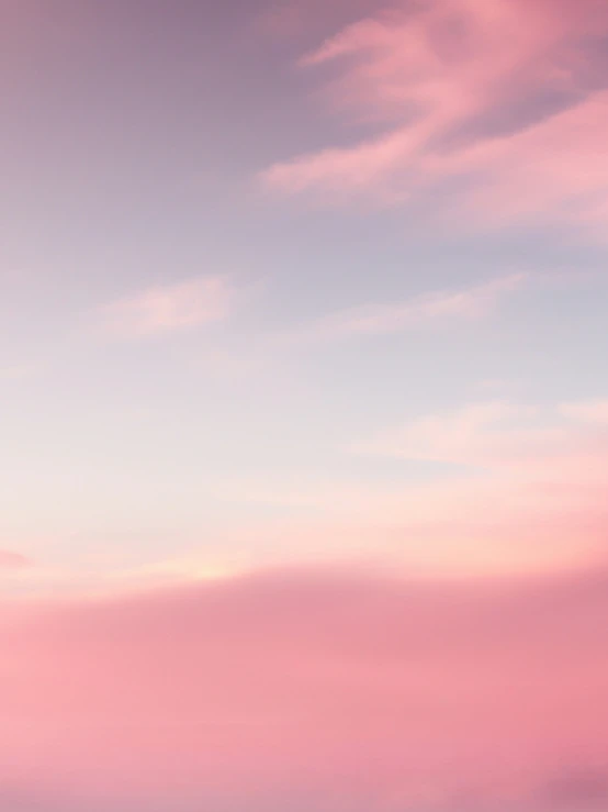 an airplane flies across a pink and blue sky