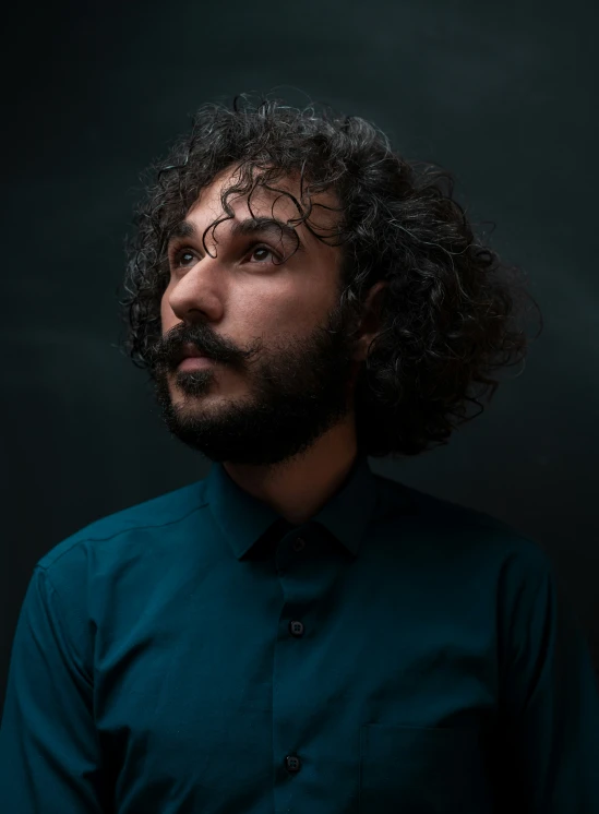 a man with curly hair and beard poses for the camera