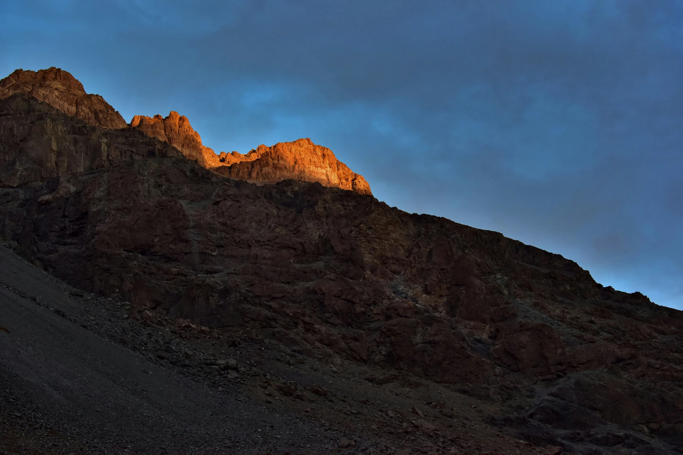 the sun is setting in front of some brown mountains