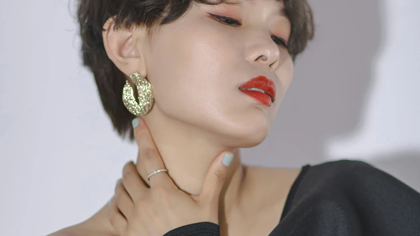 the girl wearing the earrings is rubbing her neck with one hand