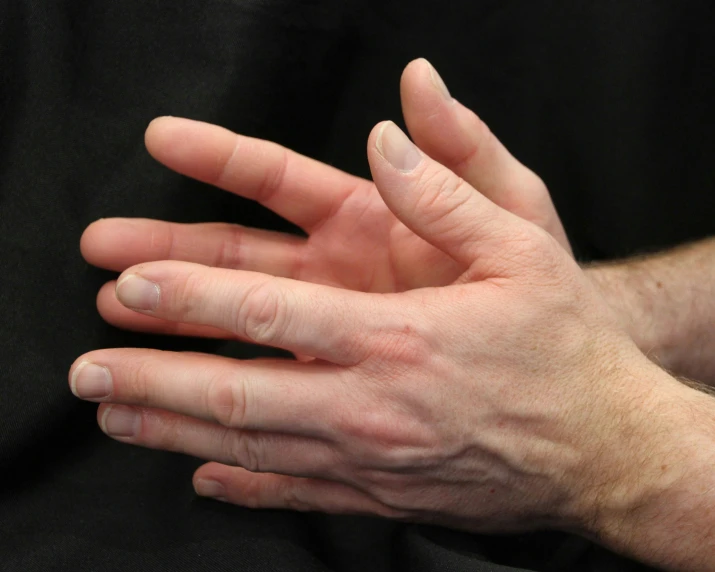 the hands are shown folded on a black background