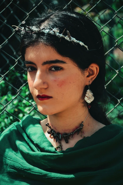 young lady with earrings, posing by a fence