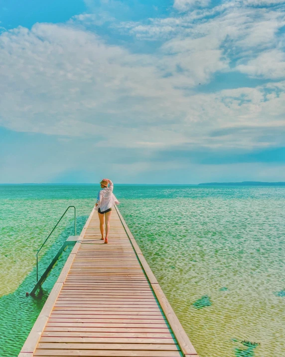 a woman standing on a wooden pier in the ocean